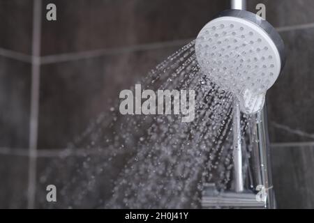 Fließendes Wasser fließt aus der Nähe des verchromten Duschmixers Stockfoto