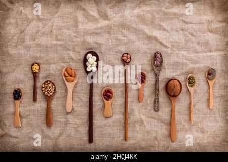 Gemischte Bohnen und Linsen in die weiße Schüssel auf braunem Hintergrund. mung Bean, Erdnuß, Soja, rote Kidney-bohnen, Schwarze Bohne, rote Bohnen, grüne Bohne, mille Stockfoto