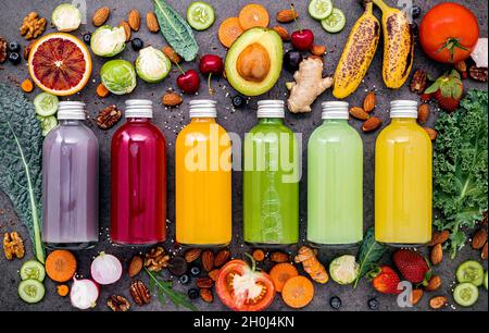 Bunte gesunde Smoothies und Säfte in Flaschen mit frischen tropischen Früchten und Superfoods auf dunklem Stein Hintergrund mit kopieren. Stockfoto