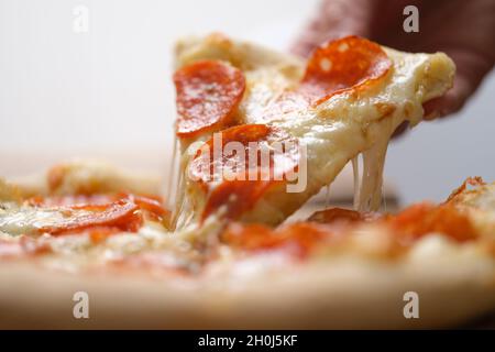 Eine Scheibe saftige, frische heiße Pizza wird aus der Nähe entnommen Stockfoto