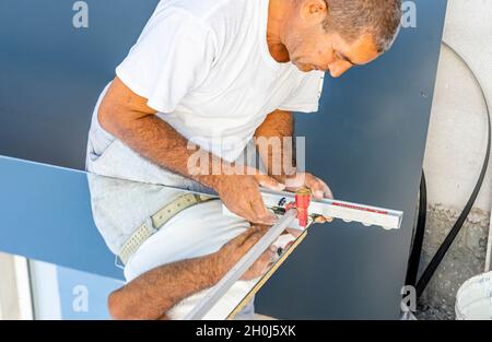 Ein Mann, der Spiegelglas mit Glasschneider schneidet, um es in der lokalen Möbelproduktion zu verwenden Stockfoto