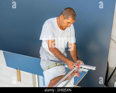 Ein Mann, der Spiegelglas mit Glasschneider schneidet, um es in der lokalen Möbelproduktion zu verwenden Stockfoto