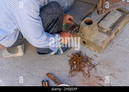 Ein Mannnailer richtet alte rostige Nägel mit einem Hammer aus, um sie später in Holzarbeiten zu verwenden Stockfoto