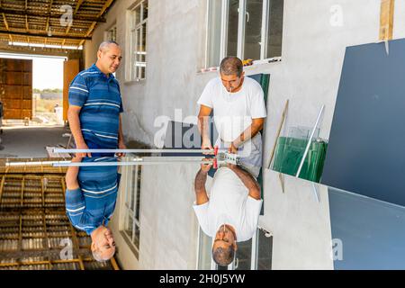 Ein Mann, der Spiegelglas mit Glasschneider schneidet, um es in der lokalen Möbelproduktion zu verwenden Stockfoto