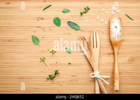 Aromatische Kräuter und Gewürze grüne Minze, Fenchel, Oregano, Salbei, Zitrone, Thymian und Pfefferminze mit Gabel und Meersalz auf Bambus Schneidebrett. Stockfoto