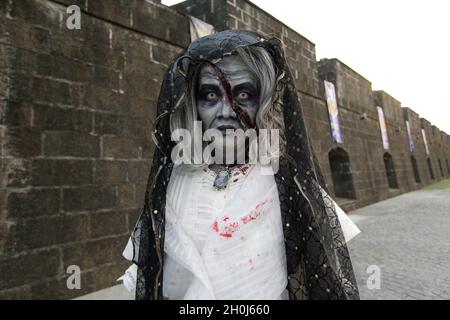 Eine Cosplayerin, die als gejagte Maria Clara verkleidet ist, eine bekannte Figur aus Noli me Tangere, einem Roman des Nationalhelden Jose Rizal, posiert während des Zombie Run-Events in Intramuros Manila, Philippinen, vor einer Kamera. Stockfoto