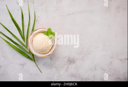 Kokoseis Aromen in der Hälfte der Kokosnuss Setup auf weißem Stein Hintergrund. Sommer und Süße Menükonzept. Stockfoto