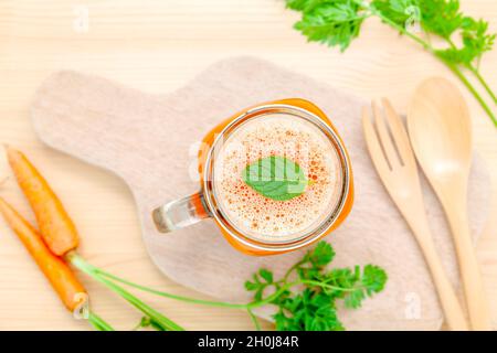 Gläser von Karottensaft mit Karotte Wurzeln auf Holz- Hintergrund. Gläser leckere frische Karottensaft. Karottensaft und Karotten. Selektiver Fokus dept von f Stockfoto