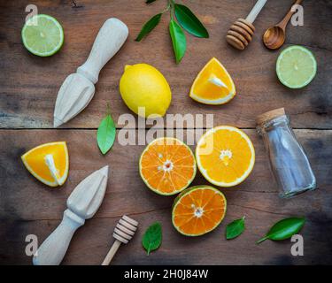 Gemischte frische Zitrusfrüchte und orange Blätter Hintergrund. Zutaten für Sommer Zitronensaft mit Entsafter und Glas Flasche. frische Zitronen, Limetten und Orang Stockfoto