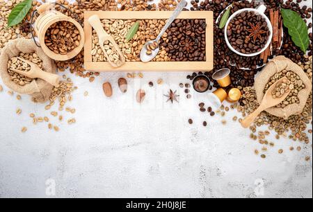 Grün und braun entkoffeiniert ungegeröstet und dunkel gerösteten Kaffeebohnen in Holzkiste mit Kugeln Setup auf weißem Beton Hintergrund. Stockfoto