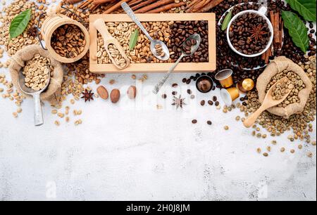 Grün und braun entkoffeiniert ungegeröstet und dunkel gerösteten Kaffeebohnen in Holzkiste mit Kugeln Setup auf weißem Beton Hintergrund. Stockfoto