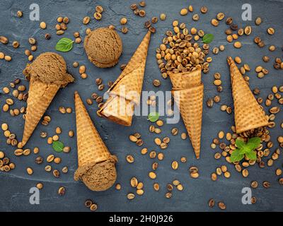 Flaches Kaffee-Eis in Waffelkegel auf dunklem Steinhintergrund. Hausgemachtes Kaffee-Eis mit Kaffeebohnen für Süßigkeiten Menüdesign. Stockfoto