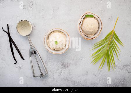 Kokoseis Aromen in der Hälfte der Kokosnuss Setup auf weißem Stein Hintergrund. Sommer und Süße Menükonzept. Stockfoto
