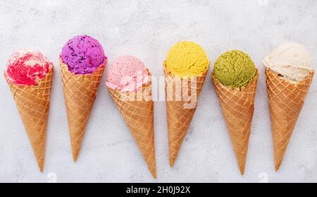 Verschiedene Eis Geschmack in Kegel Heidelbeere, Pistazie, Mandel, Orange und Kirsche Setup auf weißem Stein Hintergrund. Sommer und Süße Menükonzept. Stockfoto