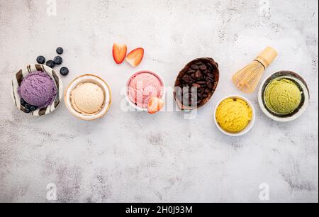 Verschiedene Eis-Aromen in Schale Heidelbeere, grüner Tee, Kokosnuss, Erdbeere und Schokolade Setup auf weißem Stein Hintergrund. Stockfoto