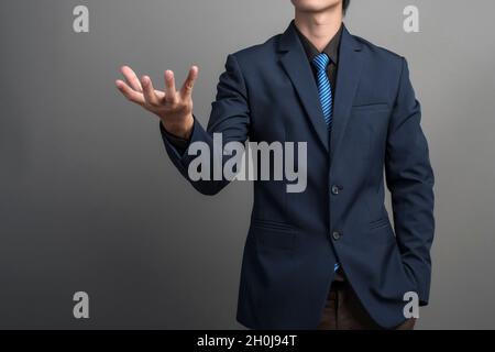 Der Geschäftsmann, der in blauen Anzug hält etwas auf grauem Hintergrund Stockfoto