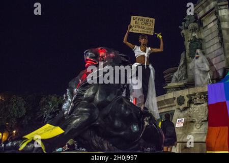 Barcelona, Katalonien, Spanien. Oktober 2021. Der Protestler ist über einer der Löwenstatuen des Christoph Kolumbus-Denkmals zu sehen, die in roter Farbe mit einem Banner mit der Aufschrift „Give Back the Gold! Reparaturen.verschiedene antikolonialistische Gruppen haben eine Demonstration aufgerufen, die die Ramblas von Barcelona der Statue von Christoph Kolumbus überließ, mit den Slogans ''Sie werden uns nicht erobern'' und ''nichts zu feiern''. Die Gruppen protestierten gegen die Feier des 12. Oktober, dem Hispanic Day. Verschiedene kulturelle Präsentationen und Aufführungen von Ureinwohnern aus lateinamerikanischen und afrikanischen Ländern h Stockfoto