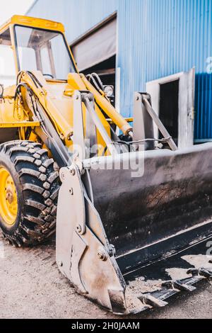 Nahaufnahme eines Eisenkaufels mit hydraulischem Antrieb an einem Radlader-Bagger gelb Stockfoto