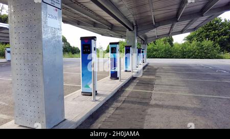 Nahaufnahme einer elektrischen Ladestation mit mehreren blauen Ladegeräten und einem leeren Parkplatz Stockfoto