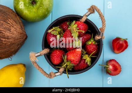 Draufsicht auf Erdbeere auf einem Korb mit Erdbeerscheiben mit Kokosnuss auf blauem Hintergrund Stockfoto