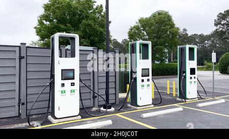 Nahaufnahme einer elektrischen Ladestation mit weißen Ladegeräten und leerem Parkplatz Stockfoto