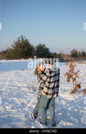 Winter Walk glücklich junge Paar Kerl und Mädchen in karierten Hemden und Jeans. Umarmung sanft, einander anschauen. Das Konzept der Gefühle, erste Liebe, Romantik. V Stockfoto