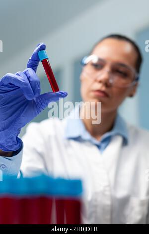 Chemiker Arzt analysiert medizinischen Vacutainer mit Blut arbeiten an mikrobiologischen Experiment in Medizin Krankenhaus Labor. Forscherin Biologin Frau, die mithilfe der Biotechnologie einen Impfstoff entwickelt Stockfoto