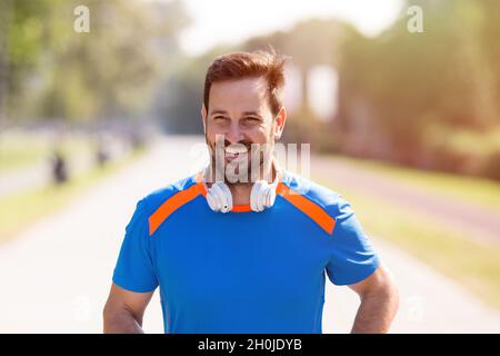 Zufriedener, gutaussehender Mann, der im Park läuft. Joggen am Morgen in der Stadt Stockfoto