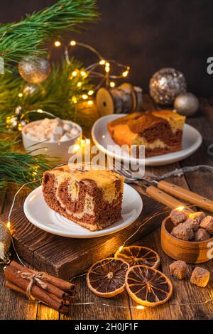 Ein Stück Zebrakuchen auf einem weihnachtlichen Hintergrund mit brennenden Lichtern. Stockfoto