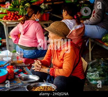 Eine Frau sitzt vor einem Tisch auf dem Hoi an Produce Market. Stockfoto