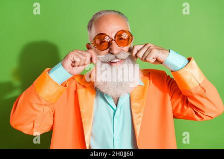 Portrait von attraktiven fröhlichen Mann trägt specs berühren Schnurrbart guten Blick isoliert über helle grüne Farbe Hintergrund Stockfoto