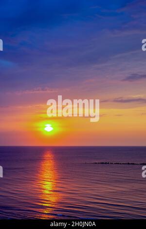 Atemberaubende Landschaft eines goldenen Sonnenuntergangs am Meer mit violettem und gelbem Ombre-Himmel Stockfoto