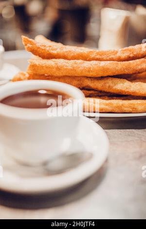 Bei Spaniern ist es üblich, Churros in eine Tasse mit heißer Schokolade zu tauchen oder ein Gericht mit Churros zu servieren, um Kaffee mit Milch zu servieren Stockfoto