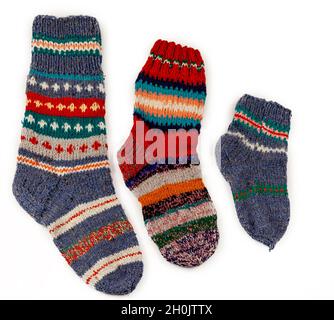 Stricksocken-Set für die ganze Familie. Warme Wintersocken aus Wolle in verschiedenen Farben mit handgefertigtem Ornament. Vintage Stricken - ein Paar Socken isoliert auf weißem Hintergrund Stockfoto