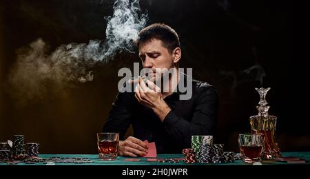 Bärtiger Casino Spieler Mann, der Poker auf dem grünen Tisch spielt Stockfoto