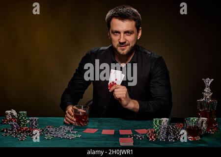 Bärtiger Casino Spieler Mann, der Poker auf dem grünen Tisch spielt Stockfoto