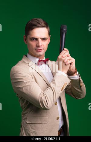Der Entertainer. Junger eleganter sprechender Mann mit Mikrofon, isoliert in einem Studio. Stockfoto