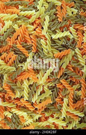 Haufen ungekochter dreifarbiger Fusilli-Pasta als Hintergrund oder Banner Stockfoto