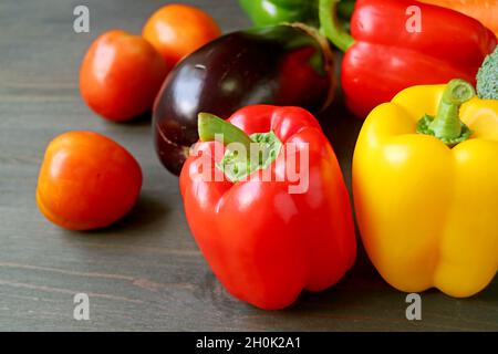 Nahaufnahme von roten und gelben Paprika mit einem anderen bunten frischen Gemüse auf einem Holztisch Stockfoto