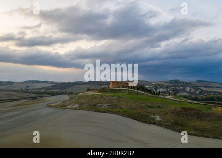 Toskana, Siena, 20. Oktober 2019. Luftaufnahme einer ländlichen Landschaft bei Sonnenuntergang in der Toskana. Ländliche Farm, Zypressen, grüne Felder, Sonnenlicht und Stockfoto