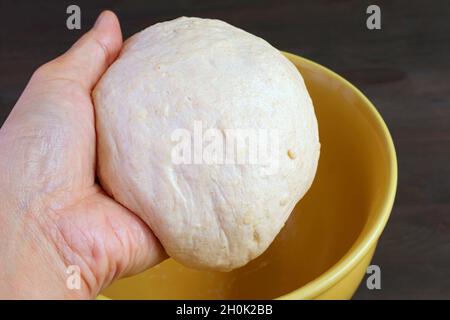 Kneteten Teig von Hand in eine Schüssel geben, damit er vor dem Backen aufgehen kann Stockfoto