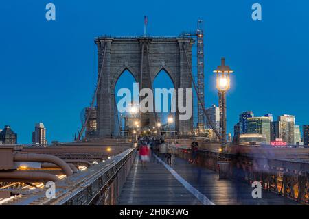 Fußgänger, die nachts über die Brooklyn Bridge laufen, New York City USA Stockfoto