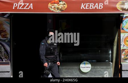 Leipzig, Deutschland. Oktober 2021. Ein Polizist steht vor einem Restaurant in der Eisenbahnstraße. Das Hauptzollamt in Dresden und die Polizei prüfen die Einhaltung der ordnungsgemäßen Zahlungen und die illegale Beschäftigung von Ausländern. Nach Angaben des Hauptzollamtes handelt es sich hierbei um eine Inspektionsmaßnahme, die nicht auf Verdacht beruht. Quelle: Jan Woitas/dpa-Zentralbild/dpa/Alamy Live News Stockfoto