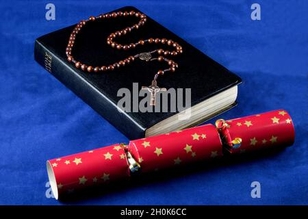 Christliche bibel mit Rosenkranz und weihnachtsknacker auf blauem Stoffhintergrund Stockfoto