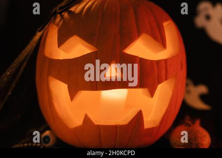 Halloween Dekoratinen auf dem Tisch. Halloween Kürbis. Traditionelle Leckereien. Große Angst Kürbis Nahaufnahme. Leuchtender Kürbis. Big Pumpin Scheule Smile Stockfoto