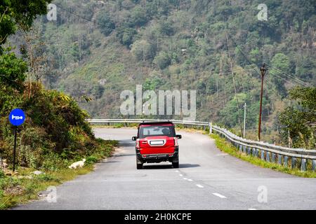 Roter Sportwagen fährt auf der offenen Himalaya-Straße Stockfoto
