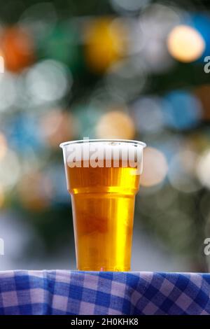 Plastikglas Bier auf Tisch mit karierter Tischdecke Stockfoto