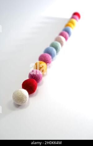 Bunte Filzkugeln in einer Reihe, Fokus im Vordergrund Stockfoto