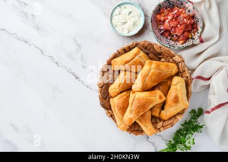 Gebratene Empanadas mit Koriander, Fleisch, Ei, Tomaten und Chilisauce auf weißem Hintergrund. Konzept des lateinamerikanischen und chilenischen Unabhängigkeitstages. Stockfoto