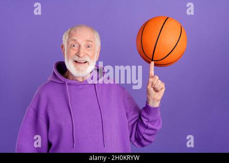 Porträt von attraktiven fröhlichen Mann Spinnen auf Zeigefinger Ball aktiven Hobby isoliert über hellen violett lila Farbe Hintergrund Stockfoto